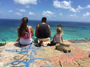 family sitting on the edge of a pillbox looking at lanikai