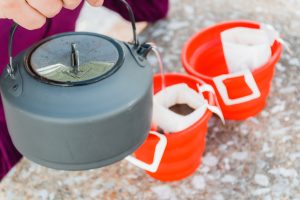 a woman pouring hot water over pour over coffee brewing bags.