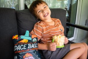 A boy eating Lesser Evil Spaceballs which is a good allergy-friendly snack for kids